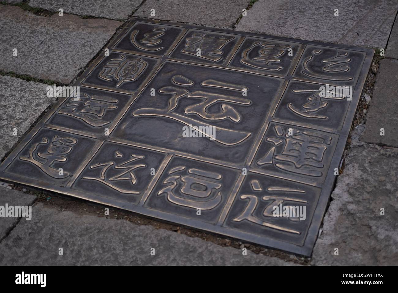 Piastrelle metalliche che simboleggiano la fortuna (Yun) secondo la cultura cinese, collocate in mezzo a una strada Foto Stock