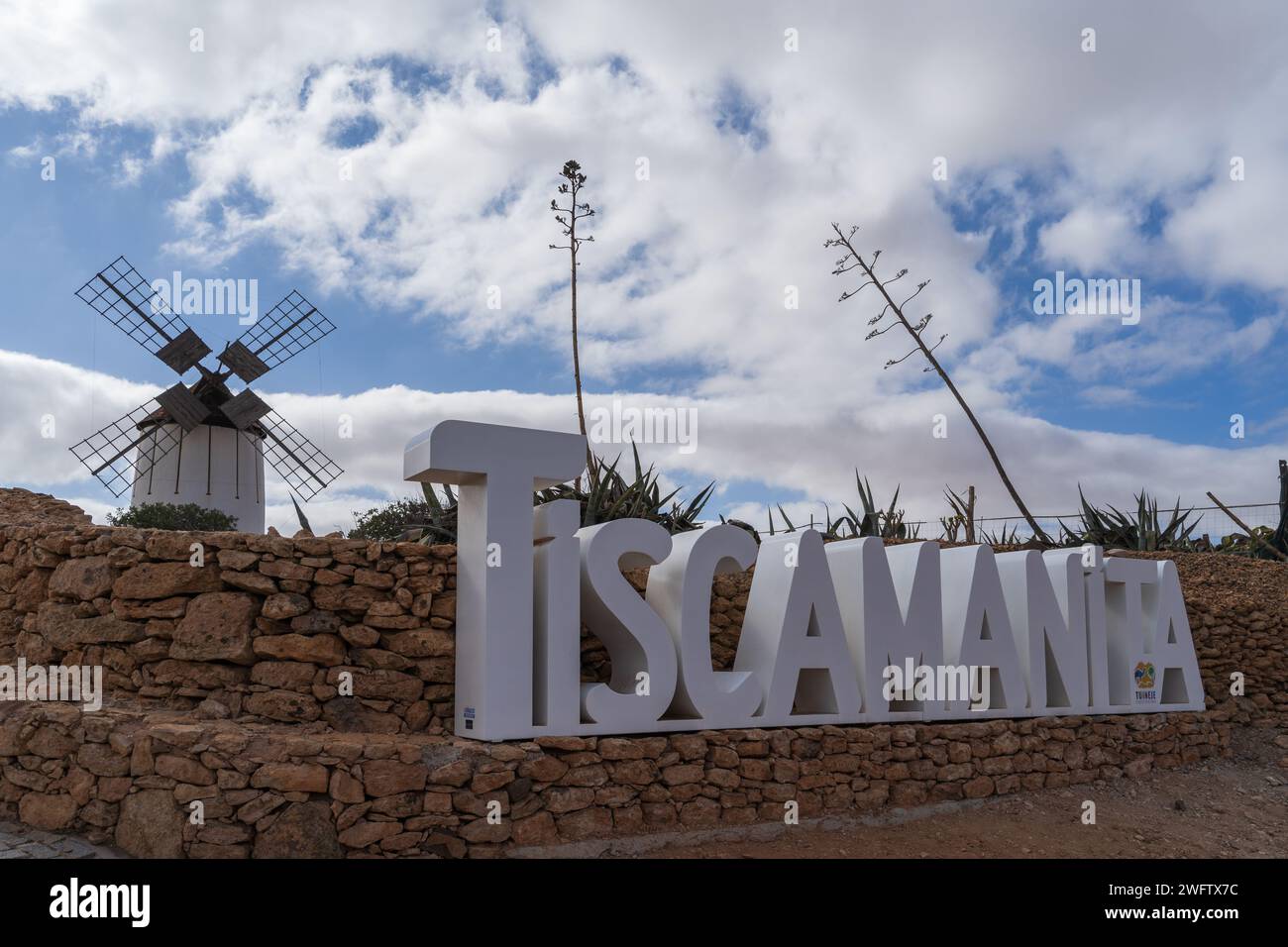 Una vista panoramica del cartello di Tiscamanita con un tradizionale mulino a vento sullo sfondo, sotto un cielo parzialmente nuvoloso. Foto Stock