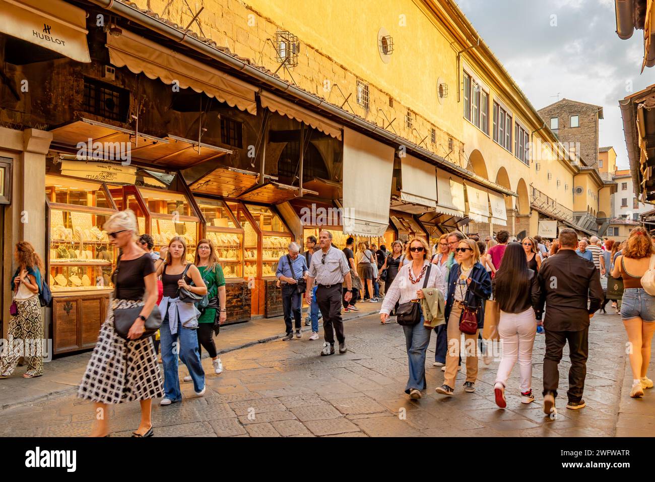Folle di persone che camminano sul Ponte Vecchio, curiosando tra le numerose gioiellerie che fiancheggiano entrambi i lati del ponte a Firenze, Italia Foto Stock