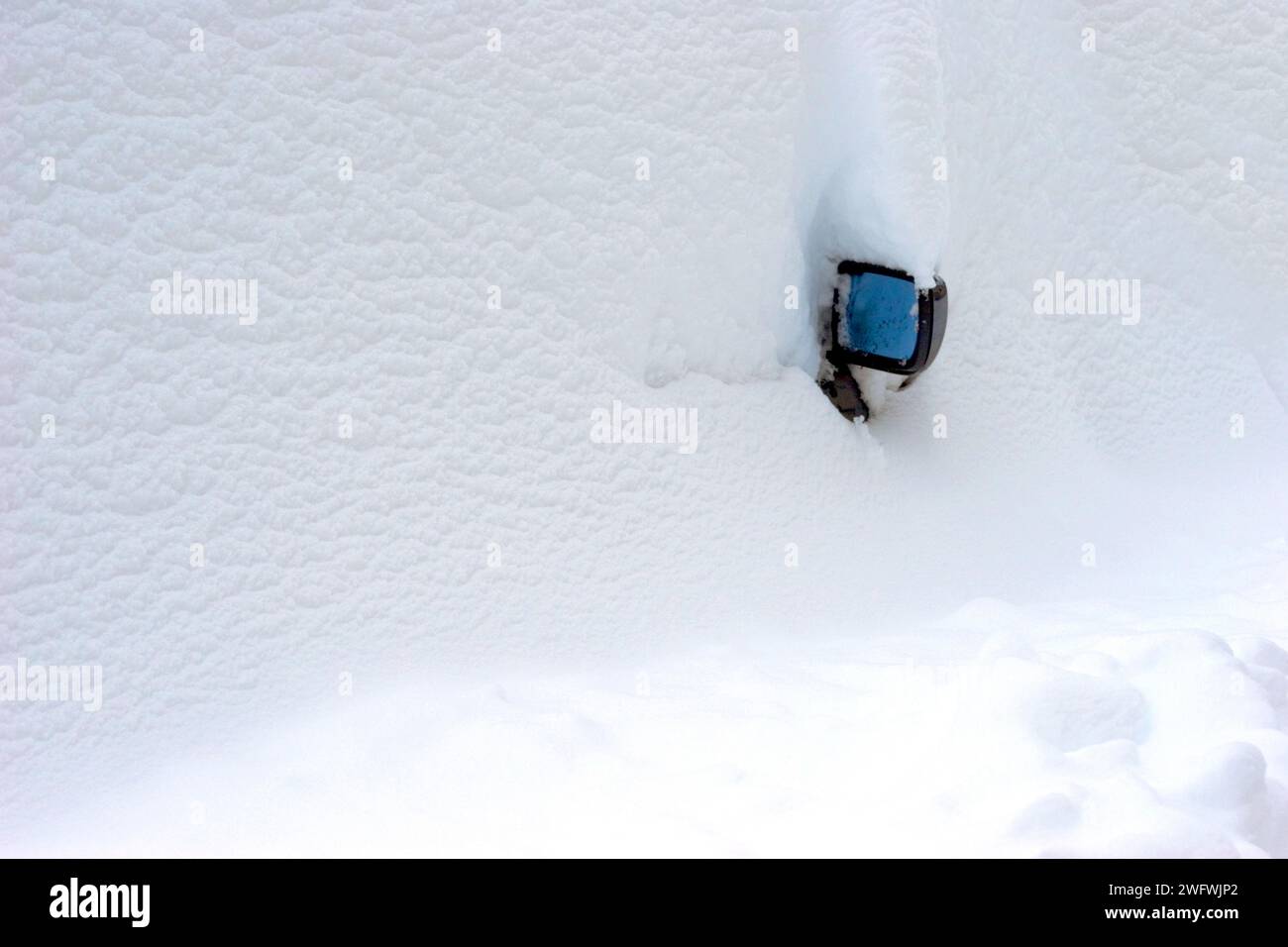 un'auto completamente nevicata, in modo che solo lo specchietto retrovisore guardi fuori Foto Stock