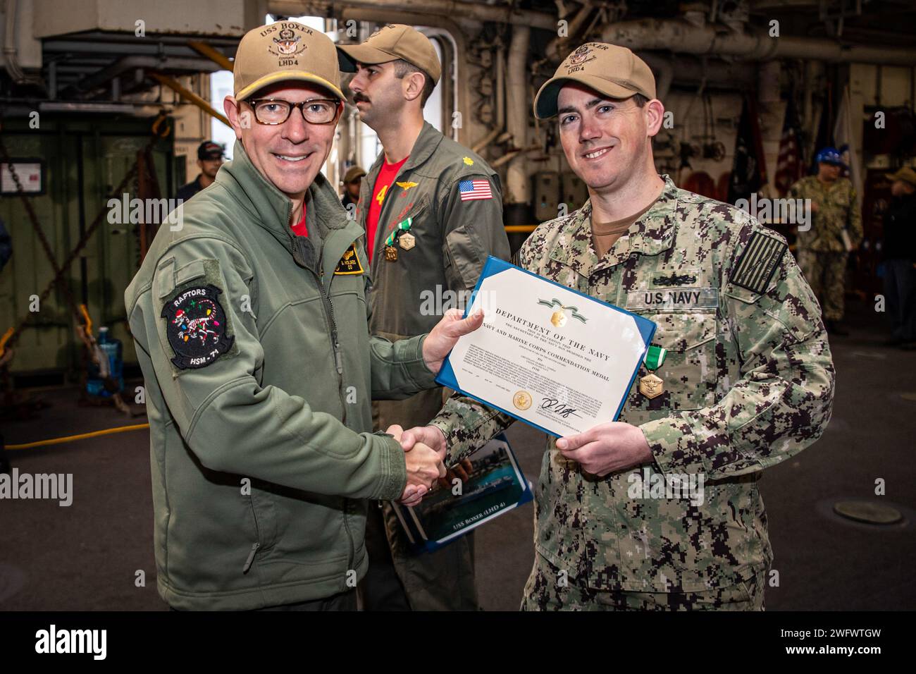 SAN DIEGO (3 gennaio 2024) - il capitano Brian Holmes, comandante della USS Boxer (LHD 4), e nativo di Winchester, Massachusetts, presenta la Navy and Marine Corps Commendation Medal al tenente Gilbert Temple, nativo di Exeter, Maine, nel ponte superiore dei veicoli. Boxer è una nave d'assalto anfibio della classe Wasp, portata in casa a San Diego. Foto Stock