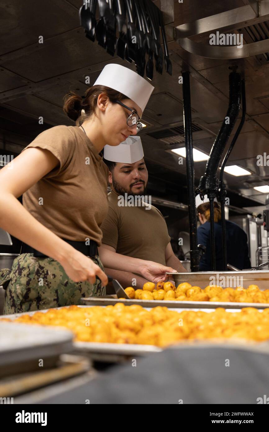 240116-N-OM737-1013 MAR MEDITERRANEO (16 gennaio 2024) Specialista culinaria marinara recluta Valeria Rivera David, assegnata alla nave d'assalto anfibio classe Wasp USS Bataan (LHD 5), prepara le patate per la cena nella galea della nave, 16 gennaio. Bataan è in un dispiegamento programmato nell'area operativa delle forze navali statunitensi in Europa, impiegato dalla Sesta flotta statunitense per difendere gli interessi alleati e partner degli Stati Uniti. Foto Stock