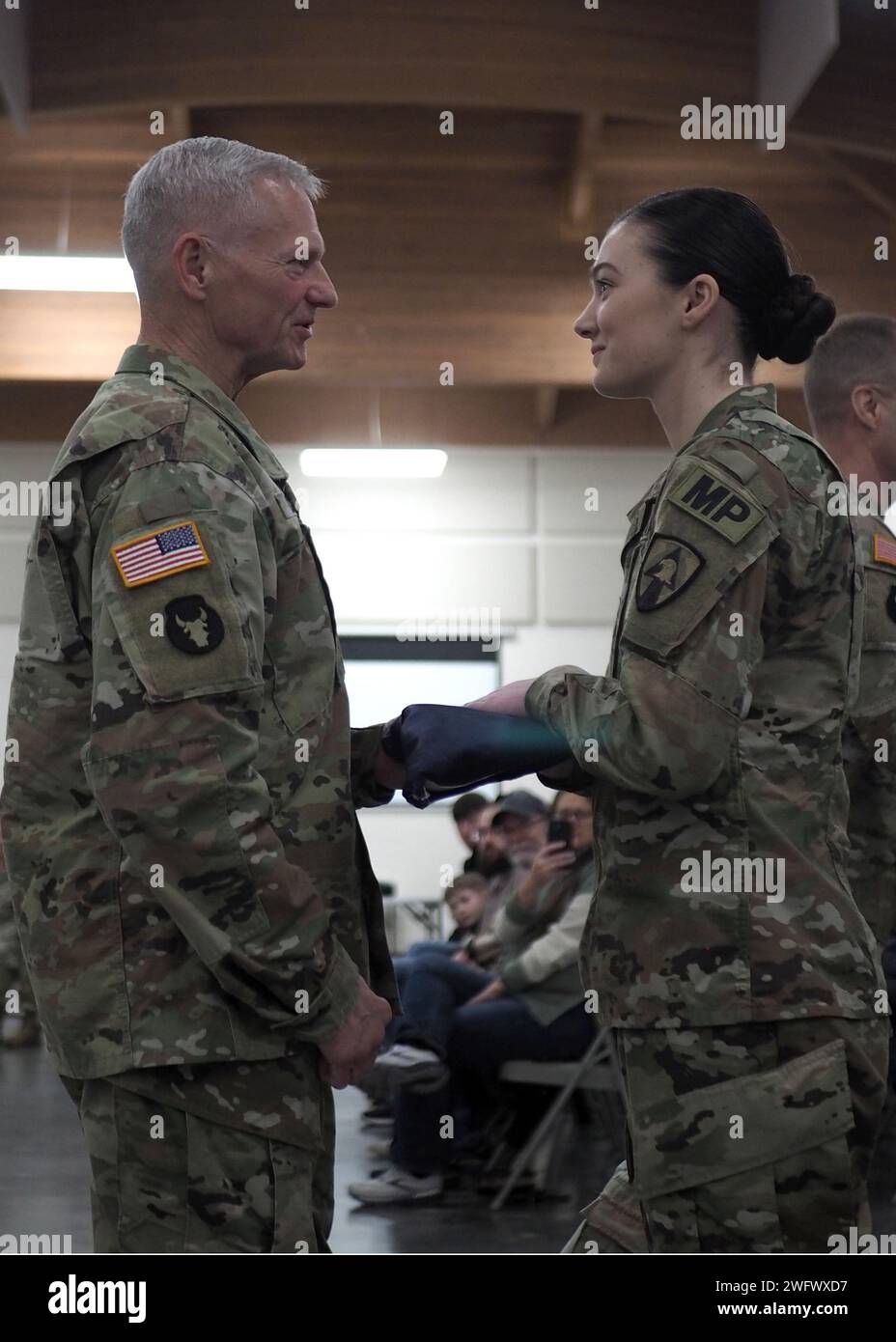 L'aiutante generale dell'Iowa, il maggiore generale Stephen Osborn dà la bandiera di stato al 2° tenente Lindsey Fuller, un leader del plotone con la 186th Military Police Company, il 734th Regional Support Group, Iowa Army National Guard, durante una cerimonia di espulsione a Camp Dodge a Johnston, Iowa, il 7 gennaio 2024. Circa 20 soldati della 186th Military Police Company si stanno schierando in Kosovo per fornire supporto legale e dell'ordine alle forze statunitensi e NATO durante l'operazione internazionale di mantenimento della pace in corso e promuovere la stabilità locale e regionale Foto Stock