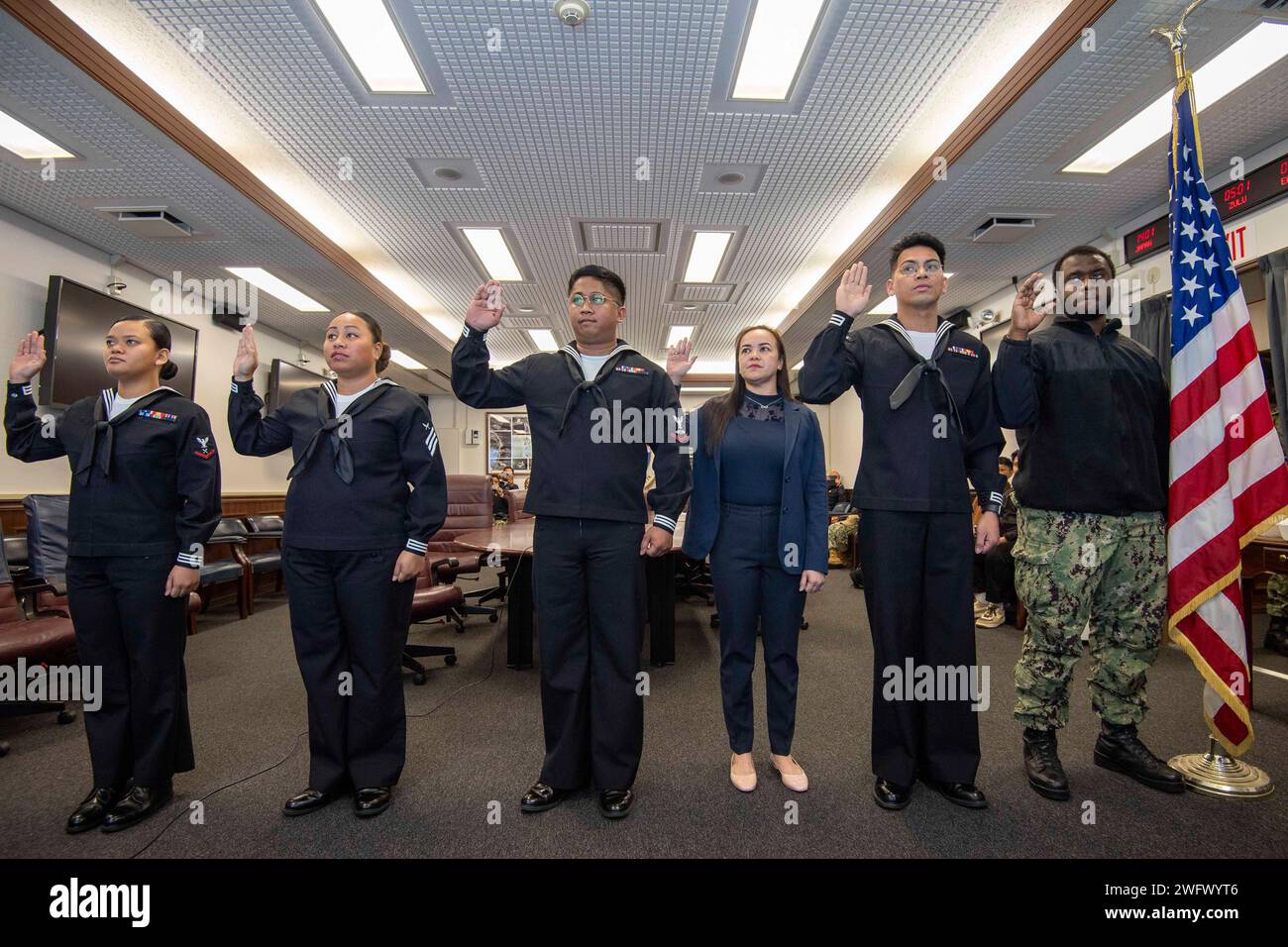 I marinai con sede a Sasebo e i membri della famiglia promettono il giuramento di fedeltà di naturalizzazione agli Stati Uniti d'America durante una cerimonia di naturalizzazione presso Commander, Fleet Activities Sasebo (CFAS) 9 gennaio 2024. U.S. Citizenship and Immigration Services and Region Legal Service Office Western Pacific ha collaborato per condurre la cerimonia di naturalizzazione presso CFAS consentendo ai marinai di diventare cittadini statunitensi. Foto Stock