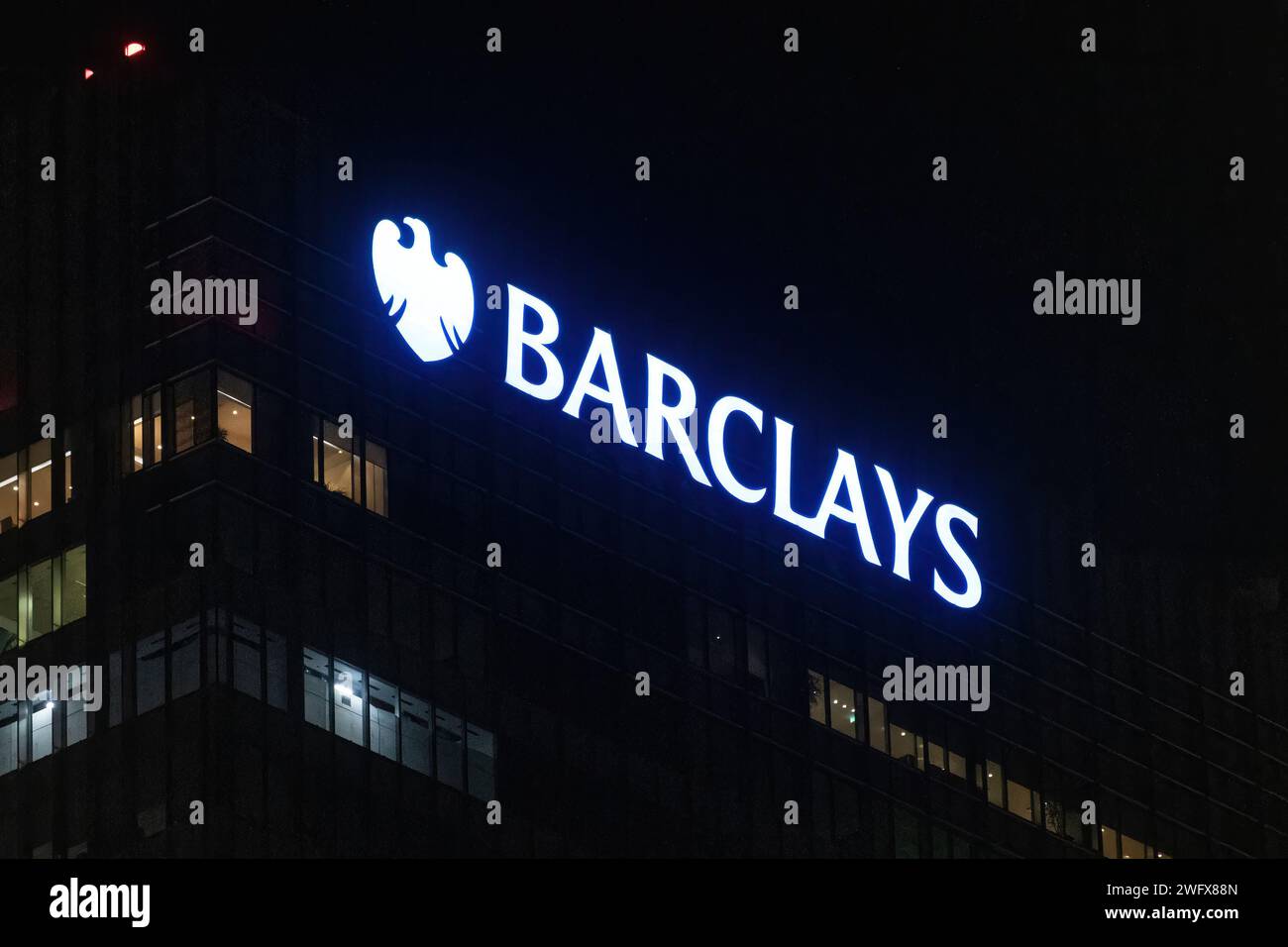 Il simbolo e il logo della Barclays Bank si illuminano di notte sul grattacielo della sede centrale della banca a Canary Wharf, Londra, Inghilterra, Regno Unito Foto Stock