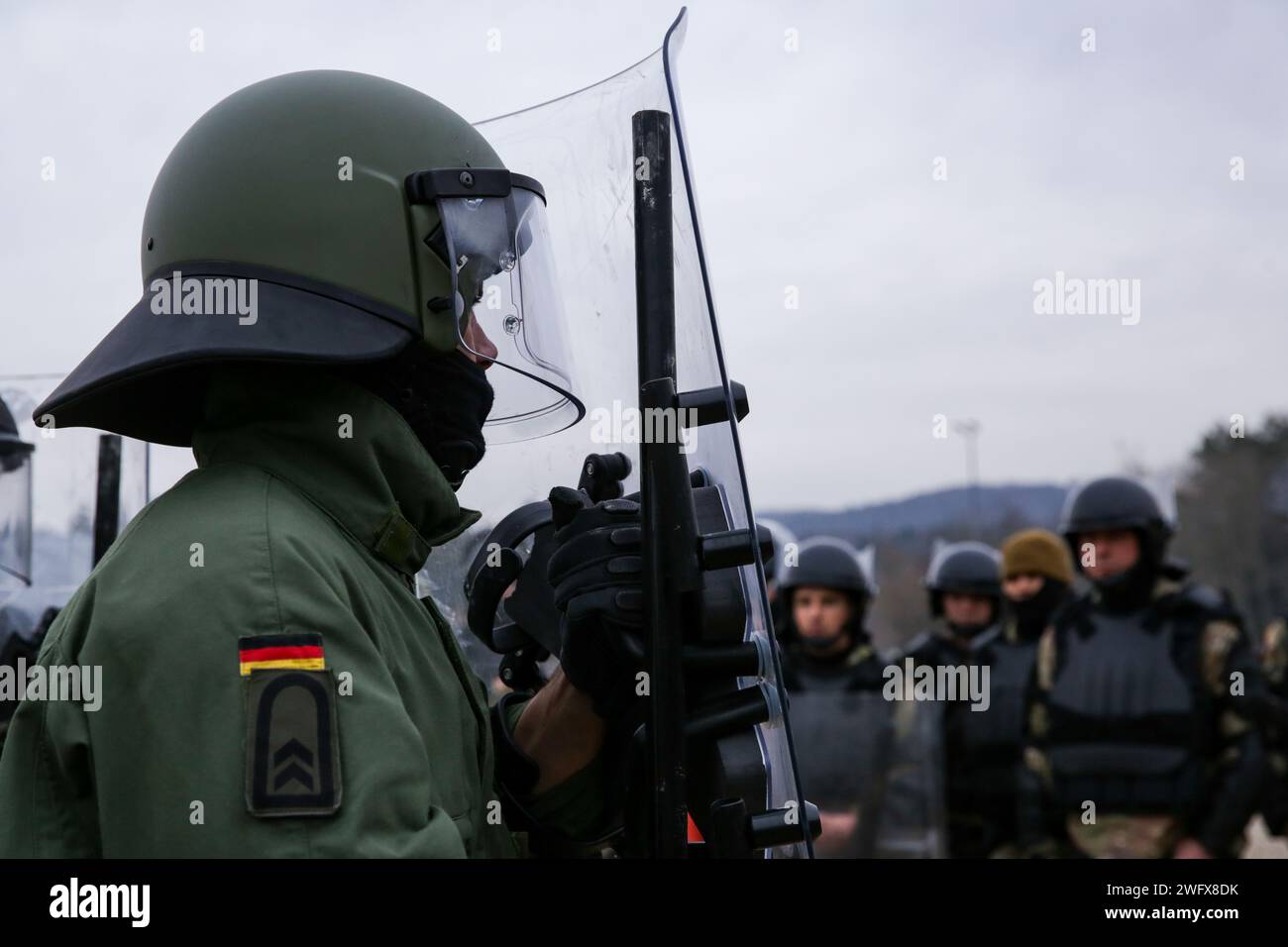 Un soldato tedesco istruisce i soldati statunitensi su come condurre il controllo della folla durante il Kosovo Forces 33 nella Hohenfels Training area, Germania, 31 gennaio 2024. KFOR 33 è un evento di formazione multinazionale condotto per preparare il 48° IBCT (GA ARNG) per il loro dispiegamento al comando regionale del Kosovo Est. Foto Stock