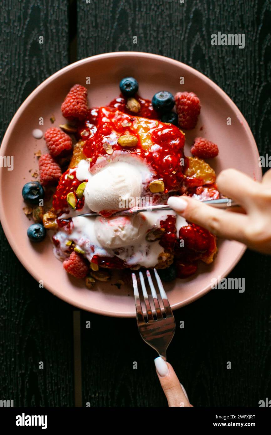 Piatto di deliziosi waffle belgi al cioccolato con gelato e mirtilli e caffè sulla vista dal tavolo Foto Stock