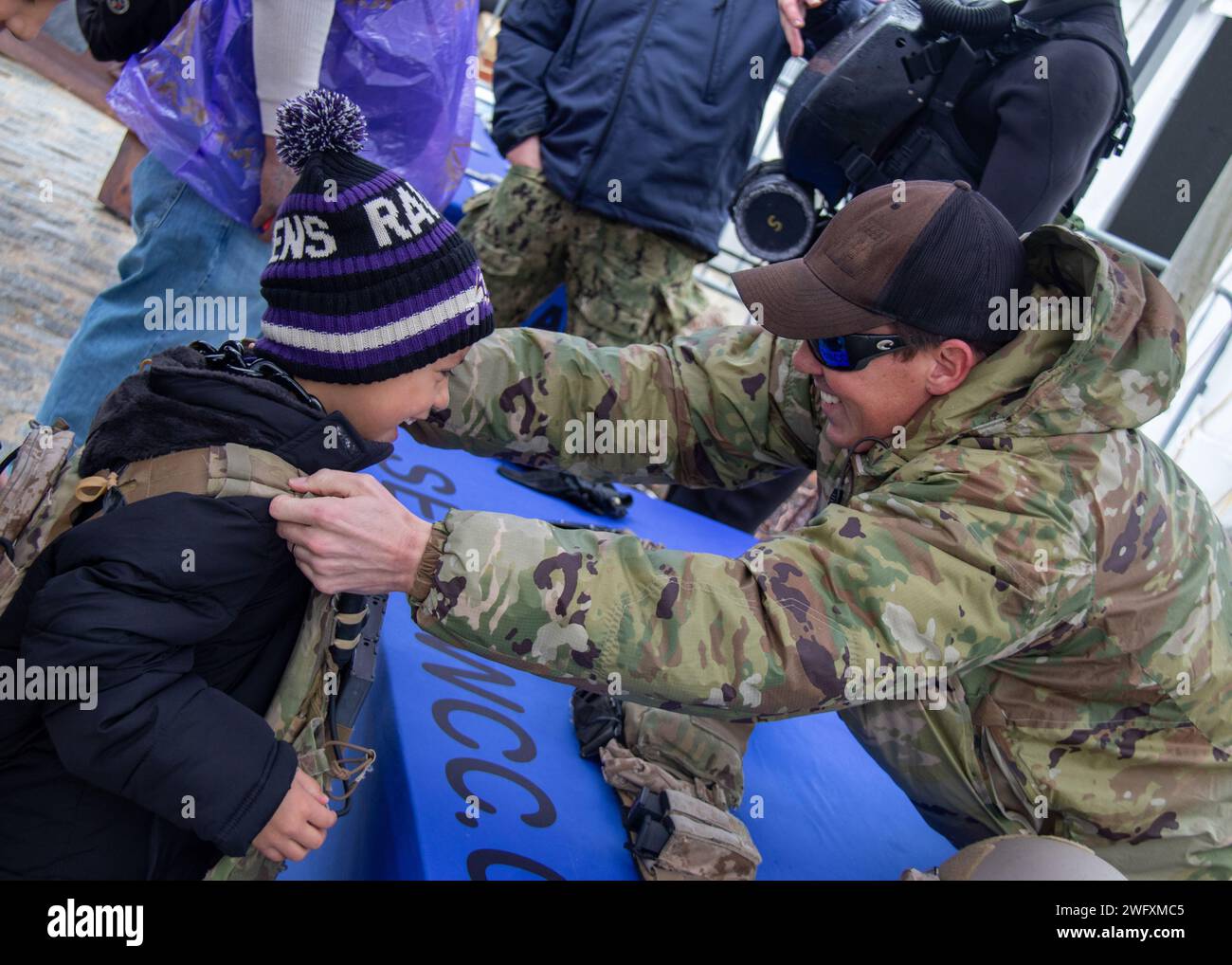 240128-N-LW994-1193 BALTIMORA (28 gennaio 2024) Un SIGILLO della Marina degli Stati Uniti aiuta un giovane TIFOSO di football a indossare un giubbotto in Kevlar durante un evento di sensibilizzazione alla partita della NFL American Football Conference Championship a Baltimora, Maryland. La Naval Special Warfare è la forza militare militare militare militare militare militare militare di élite della nazione, in una posizione unica per estendere la portata della flotta e ottenere e mantenere l'accesso per la Joint Force in competizione e conflitto. Foto Stock