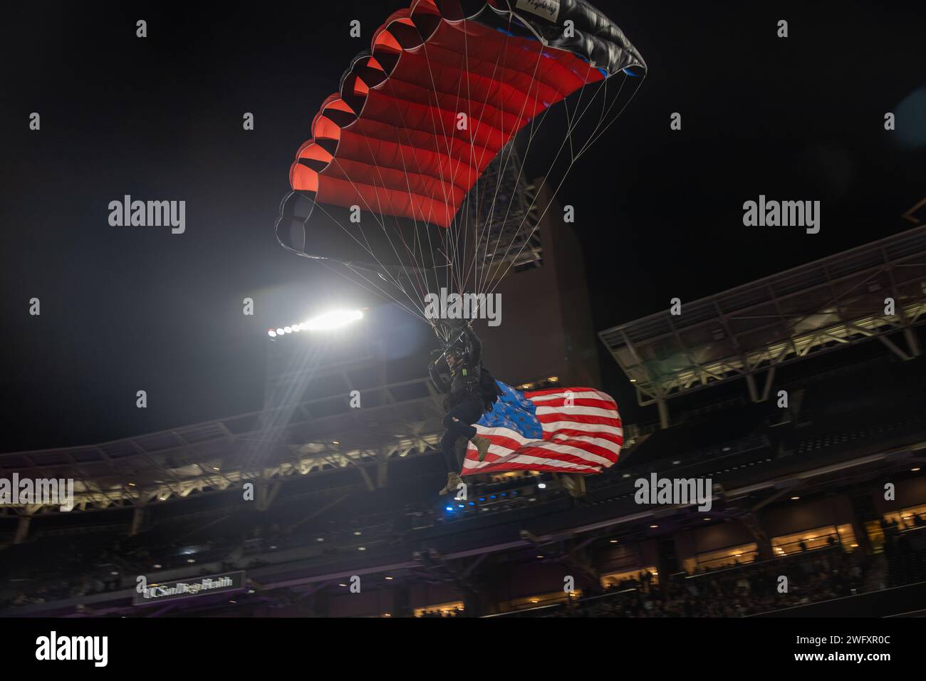Un paracadutista scivola giù con la bandiera americana al San Diego Rodeo al Petco Park di San Diego, 12 gennaio 2024. Il rodeo di San Diego ha mostrato i migliori partecipanti al rodeo del mondo mentre gareggiavano per oltre mezzo milione di dollari in montepremi durante la competizione di tre giorni. Foto Stock