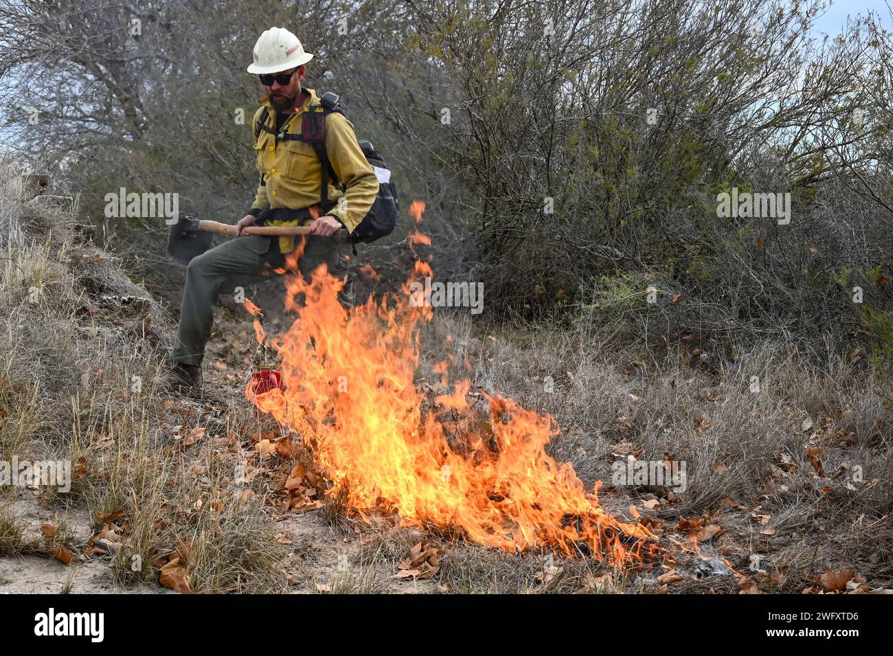 Un vigile del fuoco, con la U.S. Air Force Wildland Fire Branch, osserva la propagazione di un incendio lungo un'interruzione durante un incendio controllato presso la Laughlin Air Force base, Texas, 13 gennaio 2024. La funzione principale di un'interruzione di fuoco è quella di prevenire la propagazione del fuoco creando una barriera fisica priva di combustibile. Agisce come una linea di contenimento da cui i vigili del fuoco possono lavorare per controllare un incendio. L'obiettivo della combustione controllata era quello di ridurre l'accumulo di potenziali combustibili, come spazzole e detriti organici, riducendo la probabilità di incendi. Foto Stock