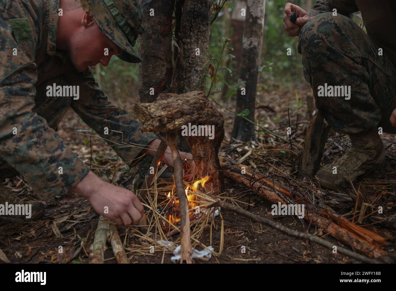 Egan Bolander, un corazzatore con 3d Battalion, 12th Marine Littoral Regiment, inizia un fuoco durante un corso di abilità nella giungla di base presso il Jungle Warfare Training Center a Camp Gonsalves, Okinawa, Giappone, 9 gennaio 2024. BJSC insegna ai Marines abilità di sopravvivenza nella giungla di base, tecniche tattiche di sospensione della corda e tattiche di guerra nella giungla per migliorare la letalità negli ambienti difficili della giungla. Bolander è nativo dell'Ohio. Foto Stock