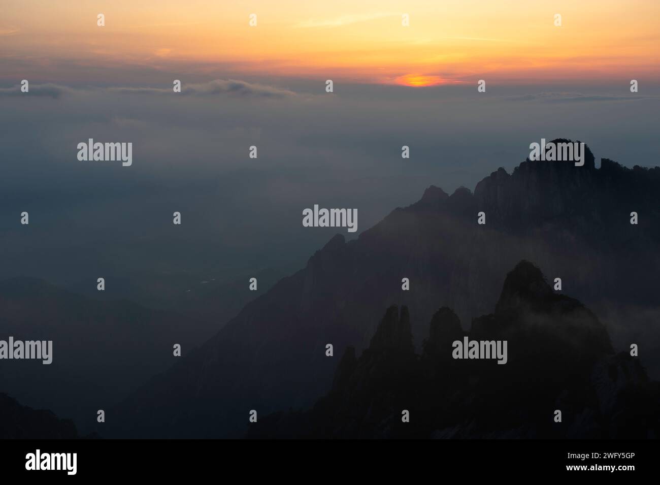 Un sole dorato tramonta sotto l'orizzonte nell'area panoramica di White Cloud, vista dal Turtle Peak nelle montagne gialle di Huangshan. Foto Stock