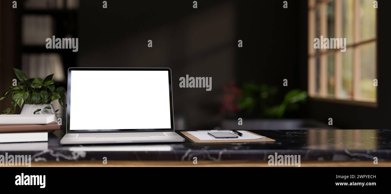 Uno spazio di lavoro moderno con un modello di laptop con schermo bianco, uno smartphone, documenti, libri e una pianta in vaso su un tavolo in marmo nero in un moderno roo nero Foto Stock