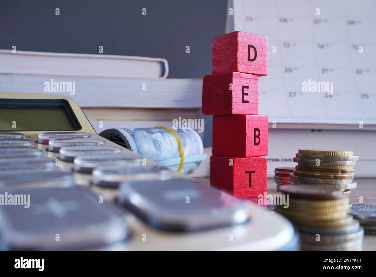 Cubi di legno con DEBITO di parole circondati da soldi e calcolatrici. Concetto finanziario. Foto Stock