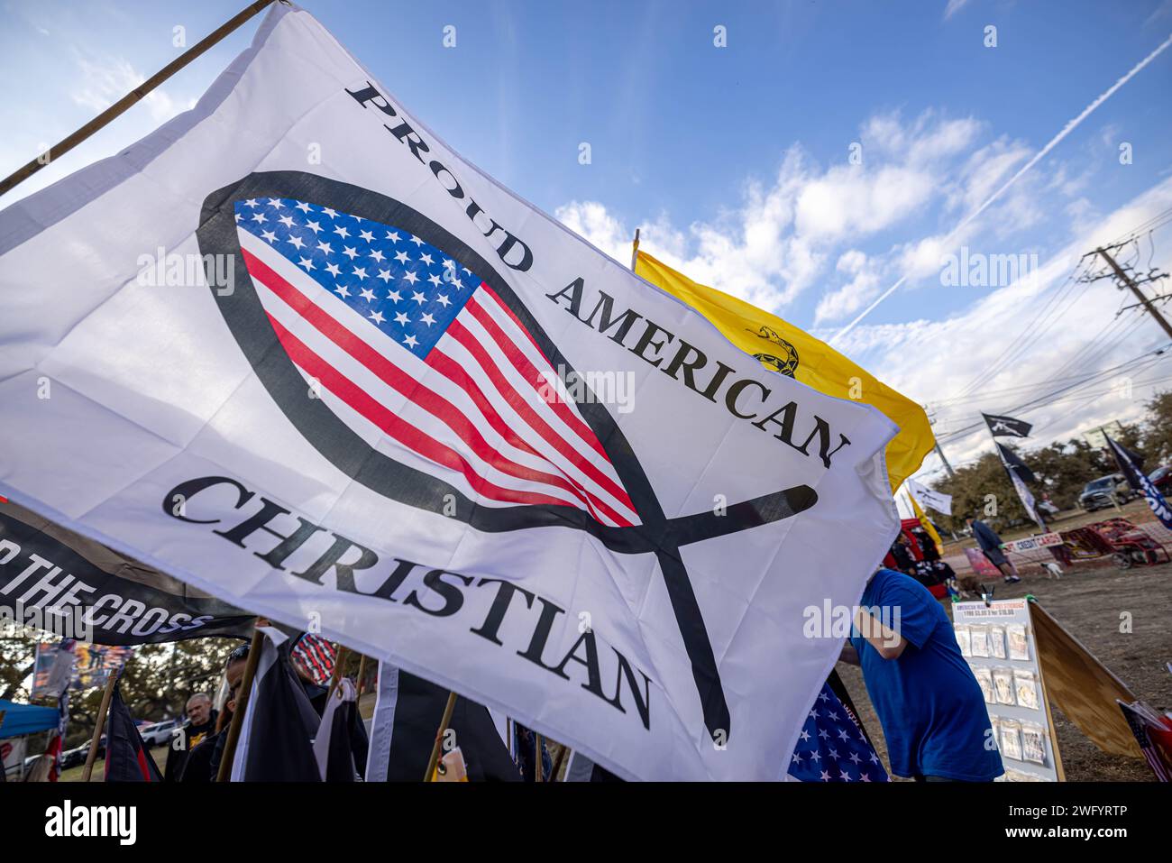 DRIPPING SPRINGS, TEXAS - 1° FEBBRAIO: Una bandiera "orgogliosa Ameican Christian" si staglia nel vento durante la manifestazione "Take Our Border Back" presso la One Shot Distillery & Brewery il 1° febbraio 2024 a Dripping Springs, Texas. Il convoglio di "patrioti", che affermano che i "globalisti" stanno cospirando per mantenere aperti i confini degli Stati Uniti per distruggere il paese, si dirigono verso il confine tra Stati Uniti e Messico, mentre la situazione di stallo tra Texas e governo federale si intensifica. (Foto di Michael Nigro) credito: SIPA USA/Alamy Live News Foto Stock