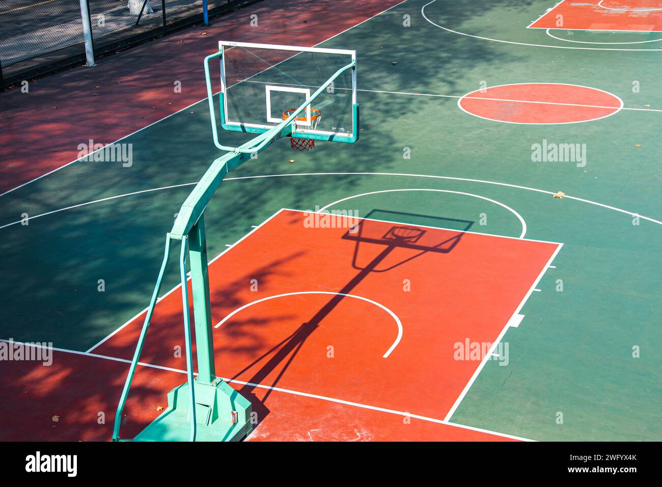 Campo da pallacanestro all'aperto, dai colori vivaci, illuminato dal caldo sole di mezzogiorno. Foto Stock