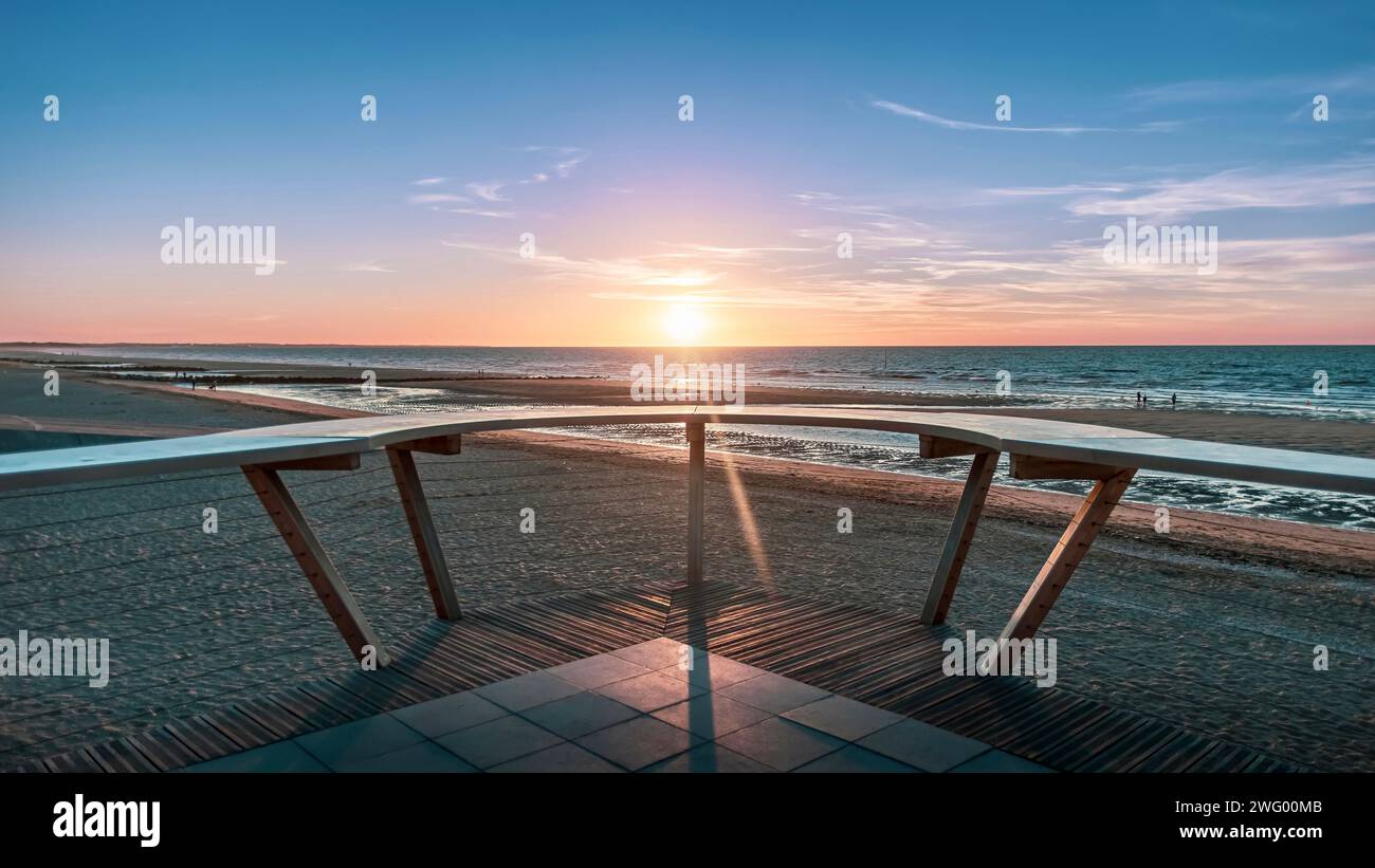 Un'alba sulla spiaggia e sull'oceano con panchine su ogni lato Foto Stock