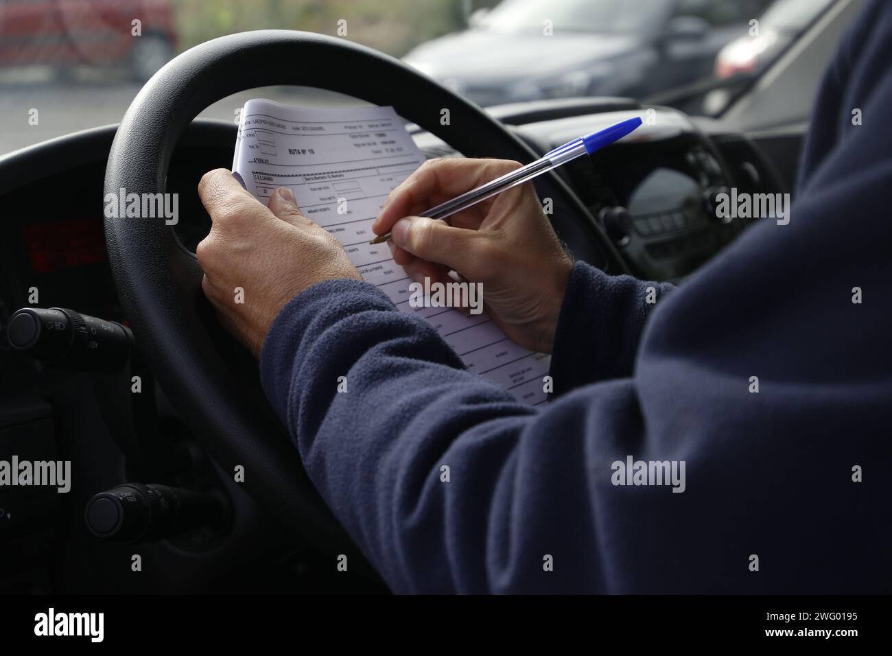 Un autista maschio che tira giù appunti seduto in un'auto Foto Stock