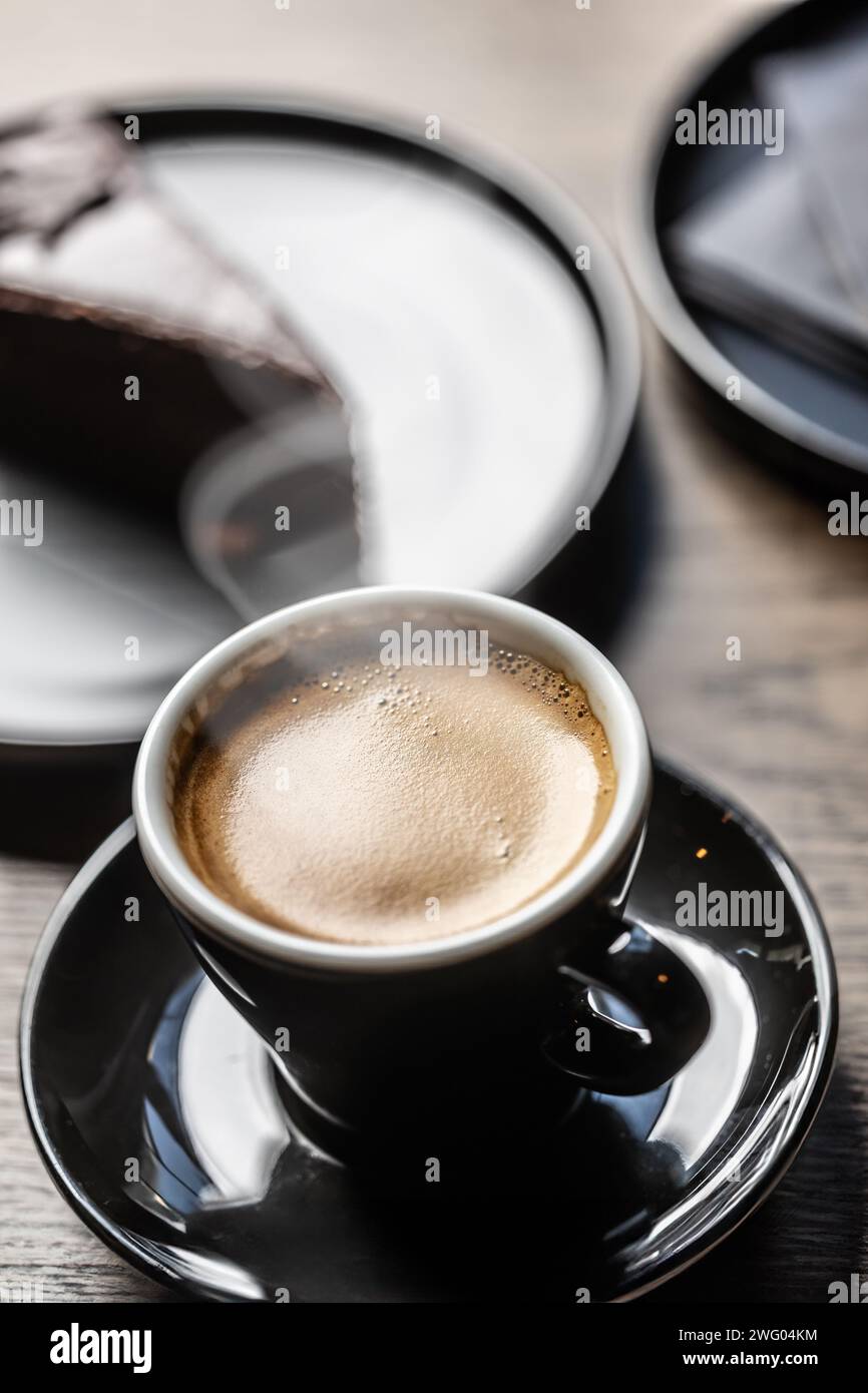 Caffè espresso tradizionale in una tazza nera su un tavolo in un caffè. Foto Stock