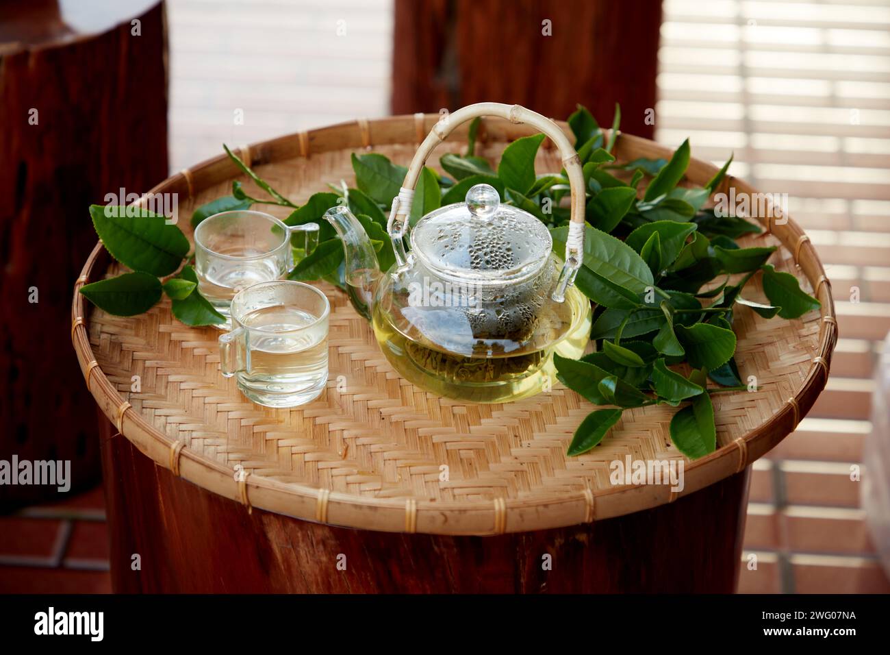 Un cestino piatto per la veranda con due tazze, teiera e molte foglie di tè verde. Fa bene alla salute delle persone, dormi bene Foto Stock