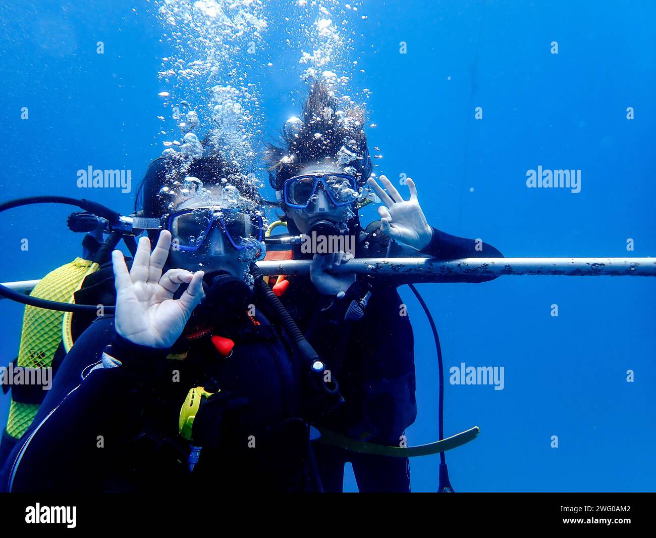 I subacquei nelle acque di Lanzarote salutano la macchina fotografica con un cartello OK, un gesto di avventura e approvazione sotto la superficie dell'oceano Foto Stock