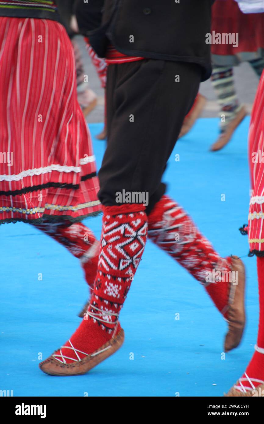 Gruppo di individui in elegante abbigliamento che si scambiano sguardi in un raduno sociale: Ballerini serbi in un festival Foto Stock