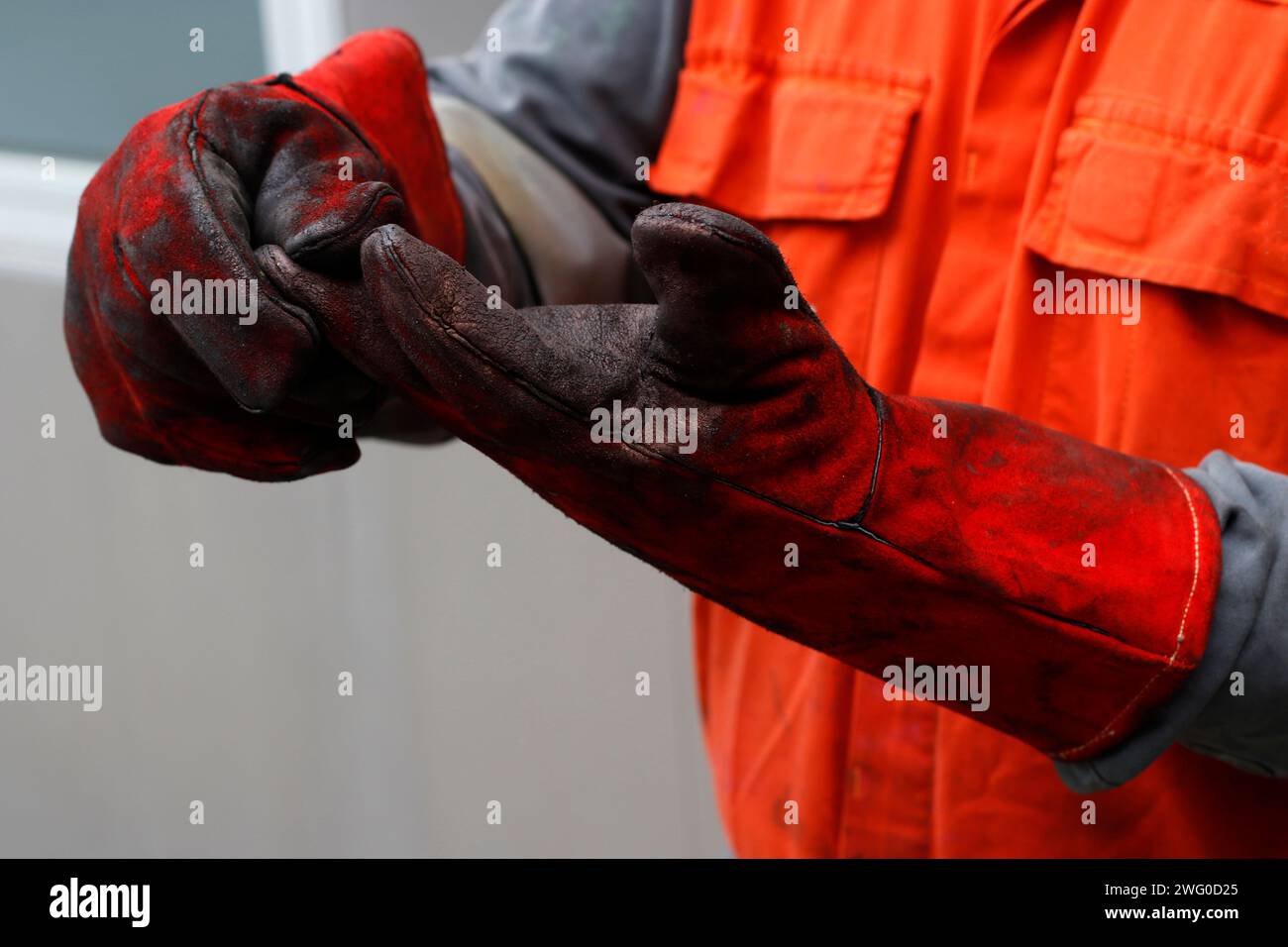 Giubbotto di sicurezza arancione che tiene un giubbotto rosso con lesioni Foto Stock