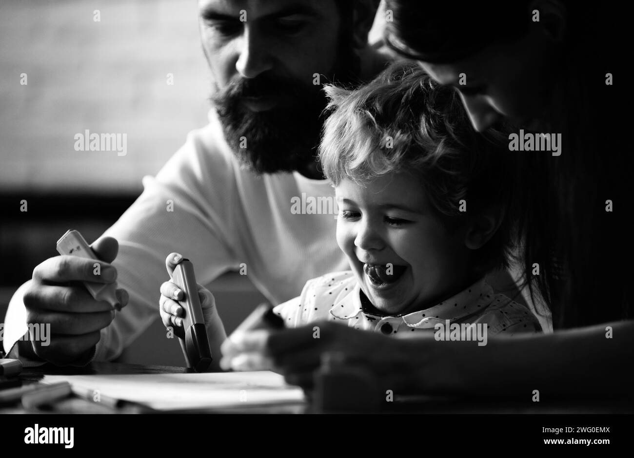 Divertimento in famiglia, felice madre, padre e bambino disegno. Famiglia amorevole felice a casa. Educazione della prima infanzia, crescita creativa dei bambini. I bambini imparano Foto Stock