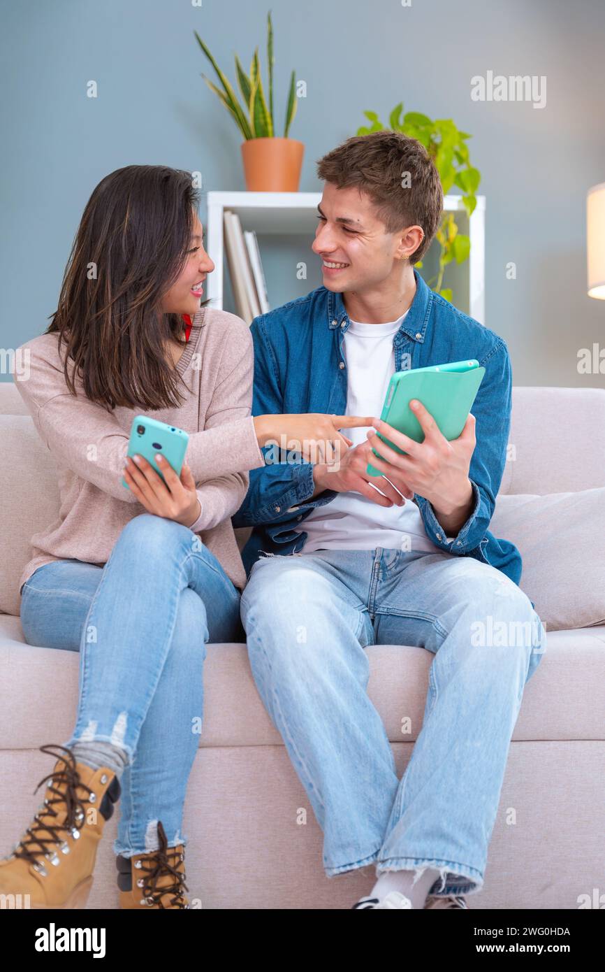 Vertical.felice multietnico uomo e donna divertiti a navigare in Internet su un tablet digitale e uno smartphone. Concetto tecnologico. Foto Stock