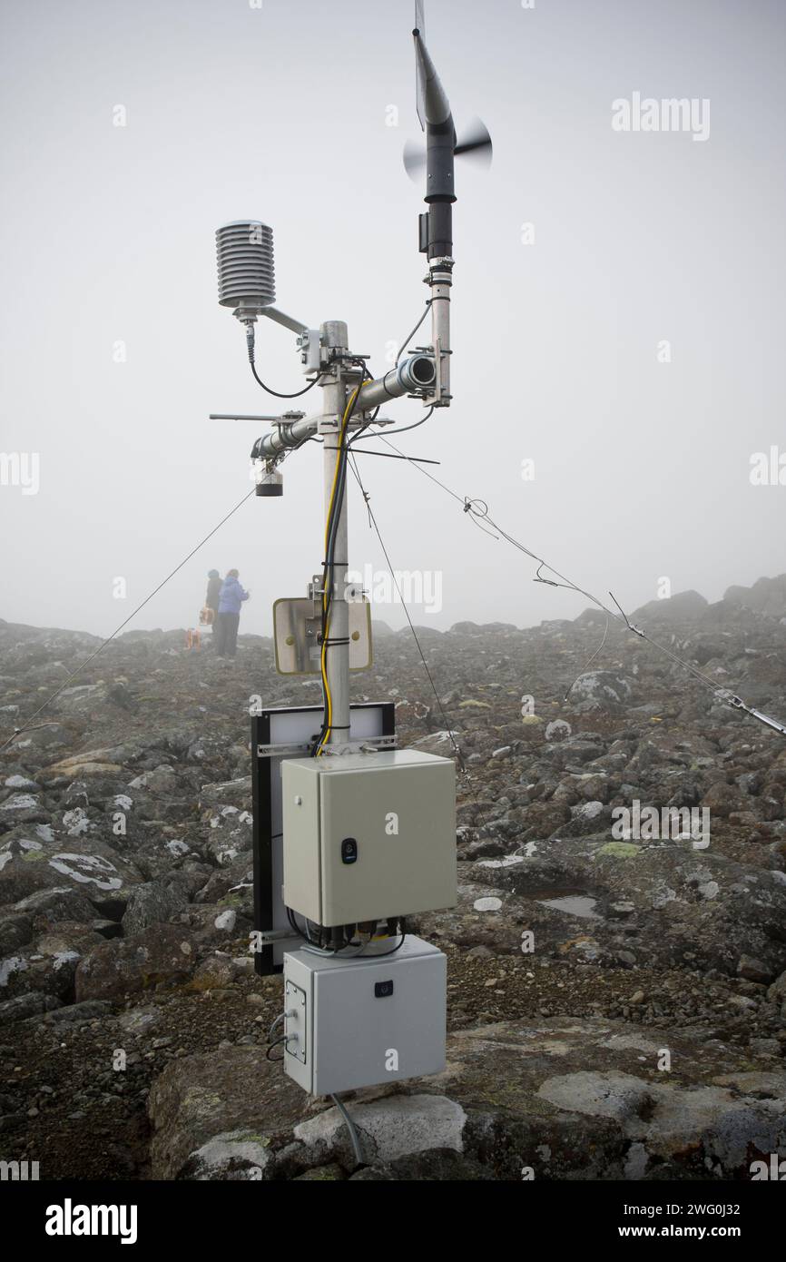 Una stazione meteorologica si trova tra le nuvole, mentre due figure lavorano su misurazioni scientifiche per gli studi sui cambiamenti climatici. Foto Stock