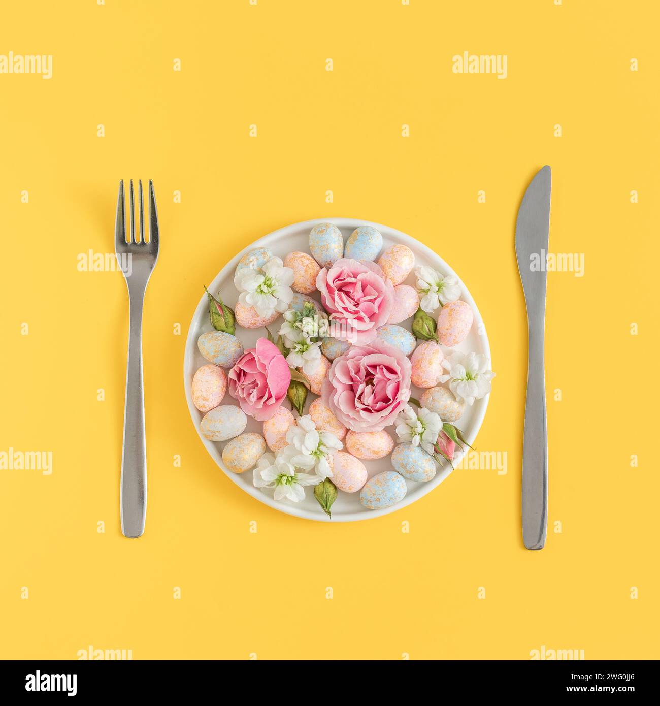 concetto di ristorazione di pasqua con uova macchiate e fiori su un piatto bianco Foto Stock