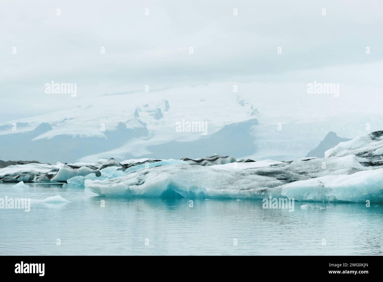 Lago glaciale naturale di Jökulsárlón con sfondo montuoso nuvoloso Foto Stock