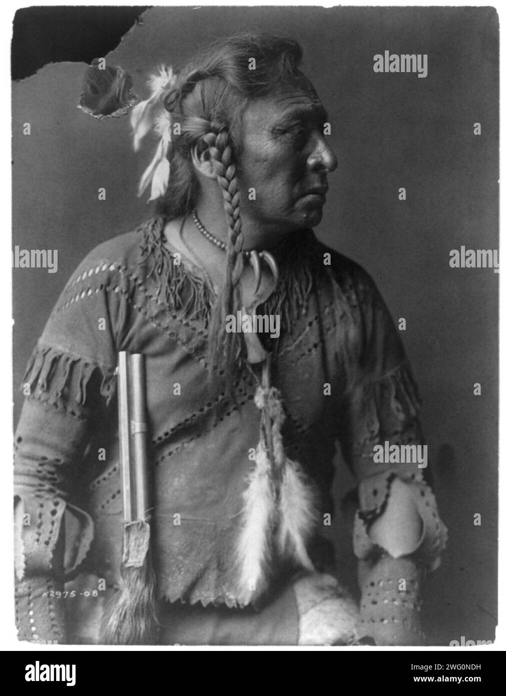 Horse Capture-Atsina, c1908. Horse Capture, ritratto a mezza lunghezza, rivolto a destra, capelli in treccia con piume sul retro, con indosso una collana con perline con due taloni e una camicia in pelle di collana; il barile di fucile a sinistra. Foto Stock