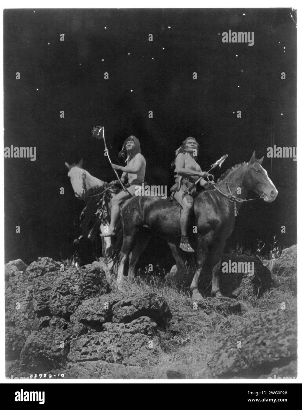 Attenzione al segnale: PERC&#xe9;, c1910. Due uomini Nez PERC&#xe9; a cavallo, con un fiocco, con la pistola nella custodia, mentre l'altro sta tenendo un bastone da colpo di stato. Foto Stock