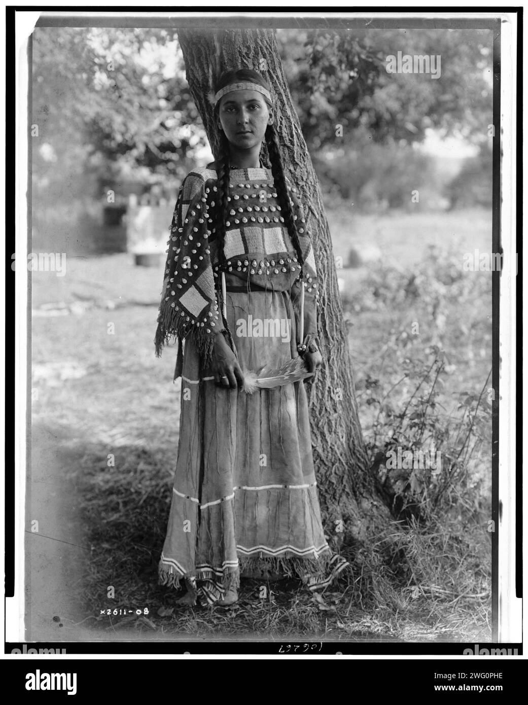 Sioux Maiden, c1908. Ritratto, a tutta lunghezza, in piedi ad albero, fascia con perline, abito in pelle di sarca con perline. Foto Stock