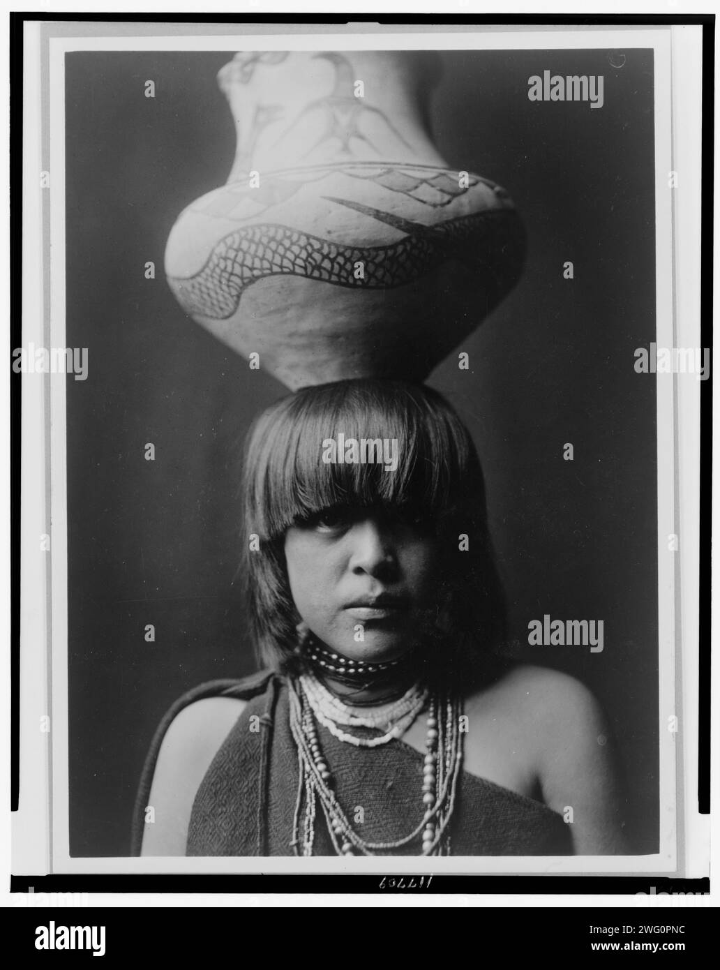 Ragazza e JAR-San Ildefonso, c1927. San Ildefonso, ritratto testa e spalle, rivolto verso la parte anteriore, con grande vaso bilanciato sulla testa. Foto Stock