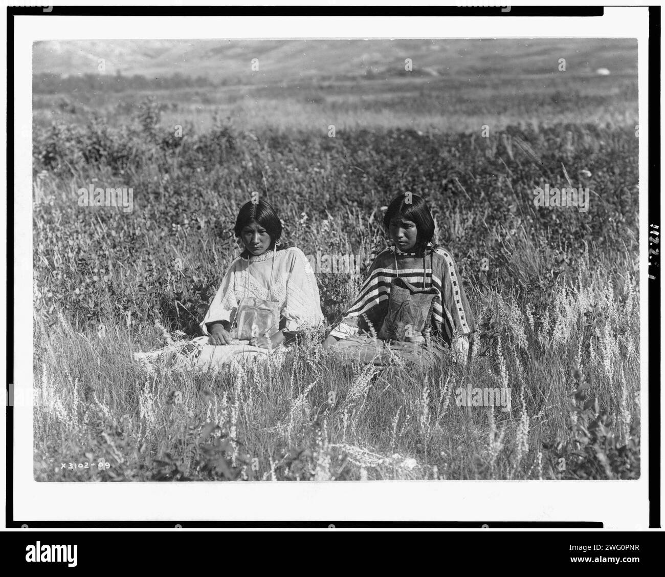 La figlia del piccolo Plume, c1910. Due giovani Piegan sedute in erba alta. Foto Stock