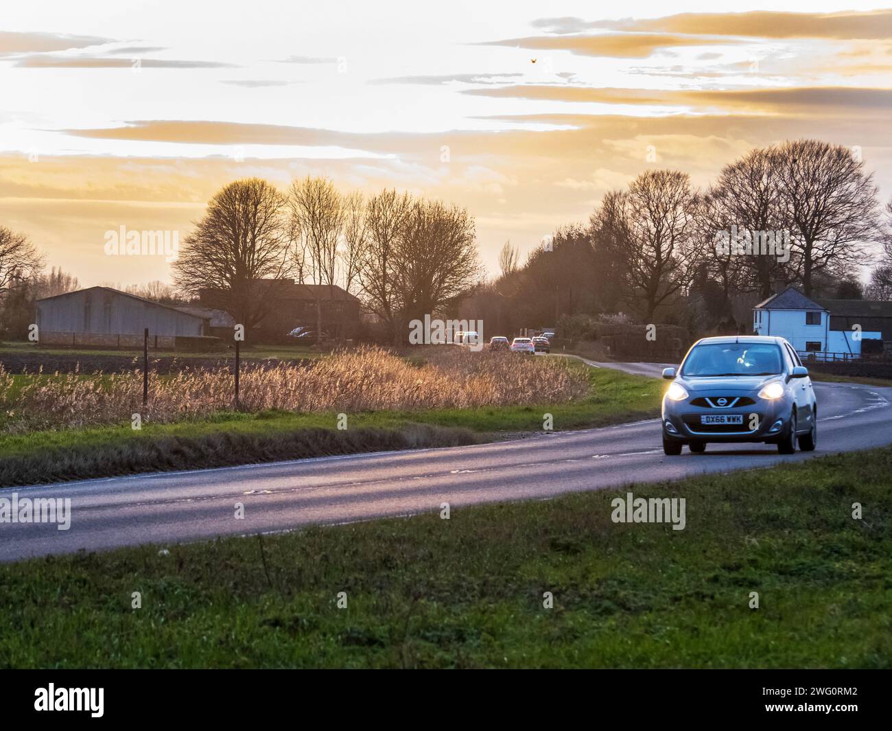 Alba dietro una strada che attraversa un terreno agricolo vicino al Nene Wash, Cambridgeshire, Regno Unito. Foto Stock