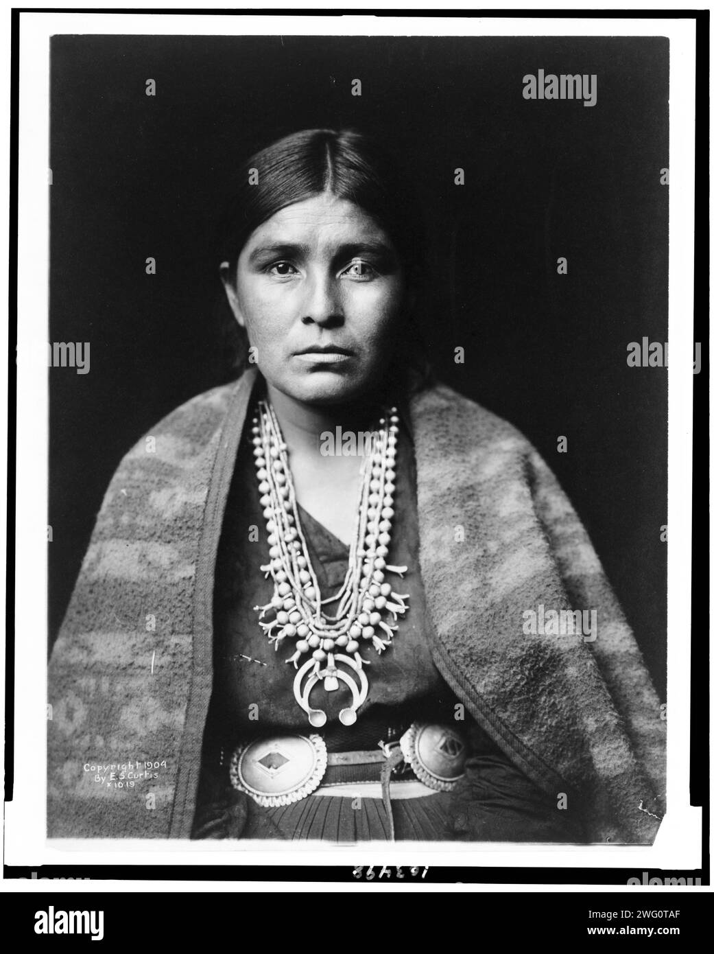 Ritratto della donna Navajo, rivolto verso la parte anteriore, c1904. Donna Navajo che indossa una collana in fiori di zucca argentati, cintura concho, coperta drappeggiata sulle spalle. Foto Stock