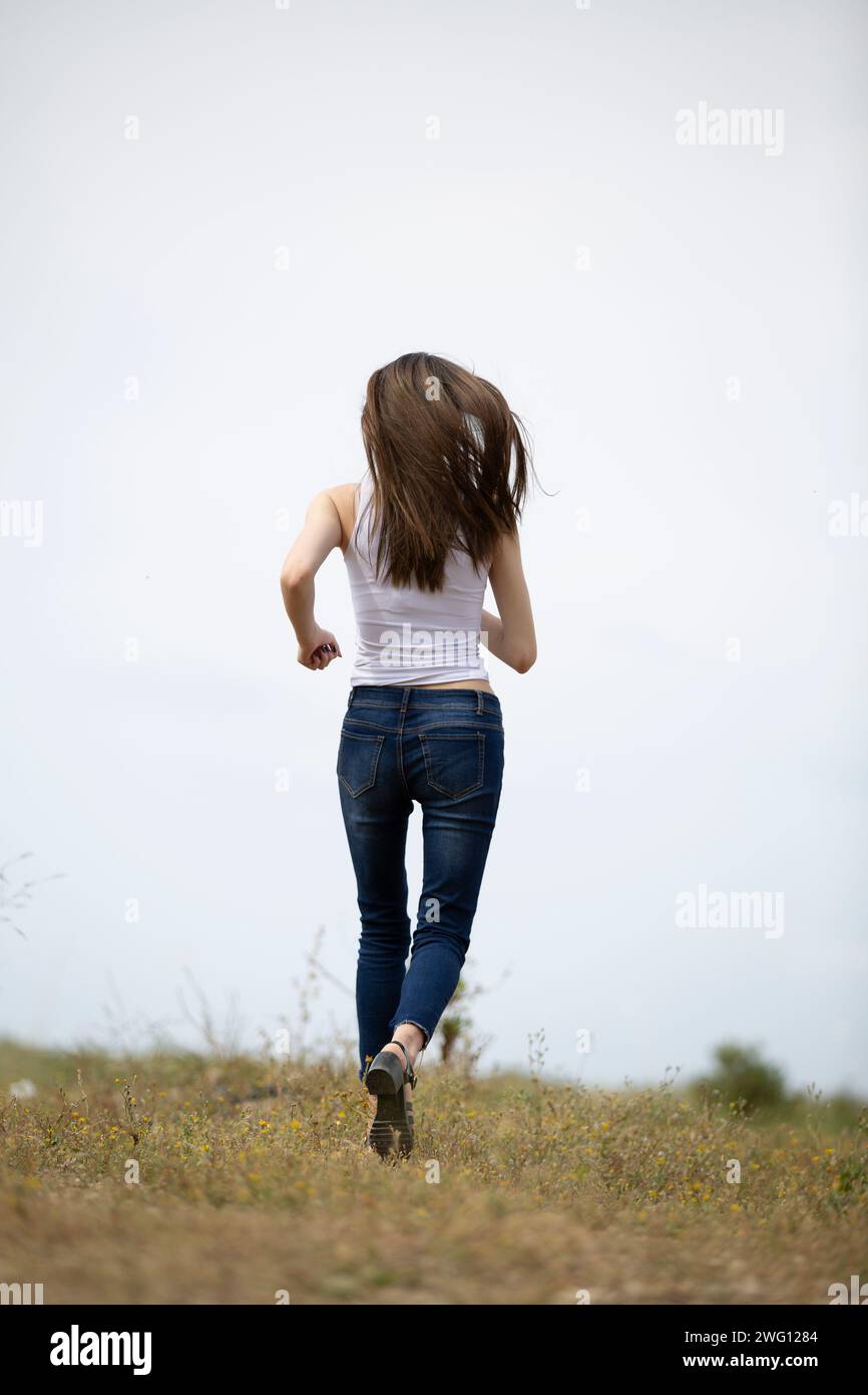 Vista posteriore della giovane donna di scappare nel campo Foto Stock