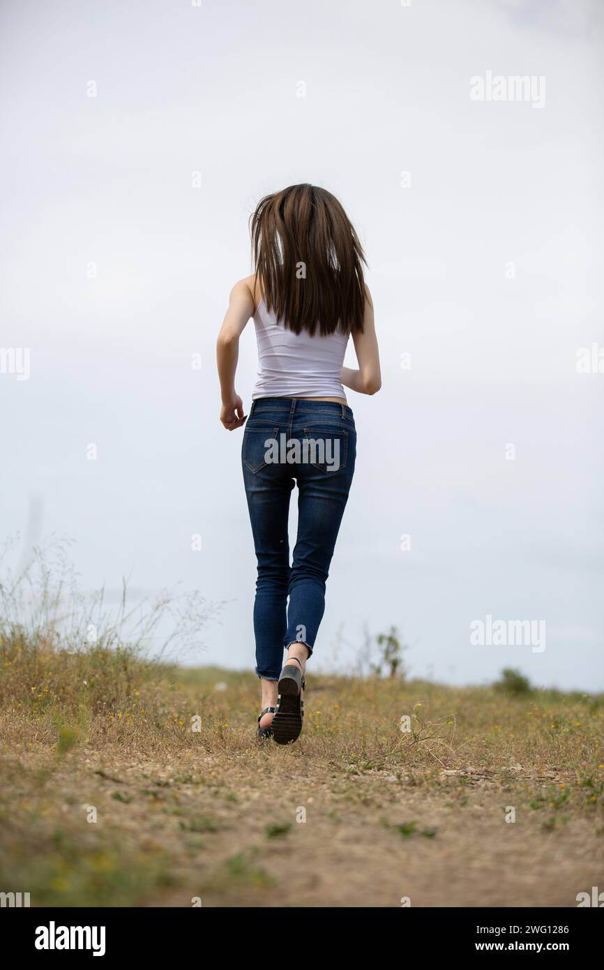 Vista posteriore della giovane donna di scappare nel campo Foto Stock
