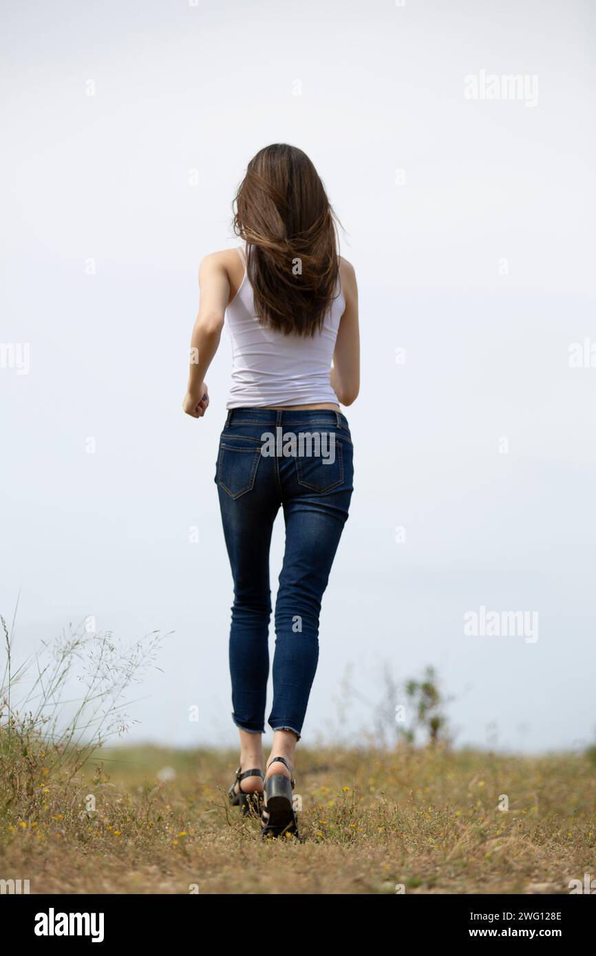 Vista posteriore della giovane donna di scappare nel campo Foto Stock