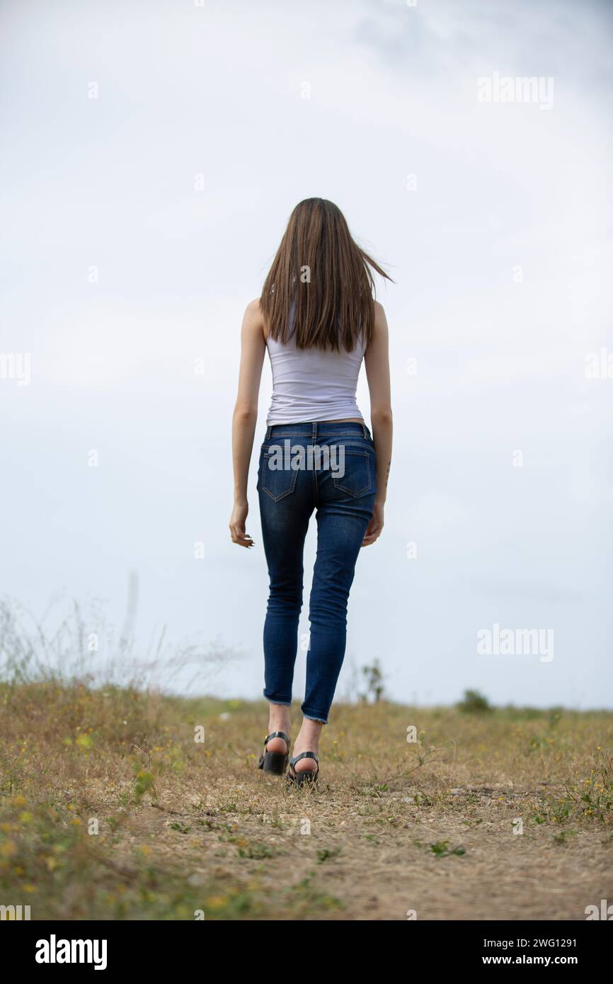 Donna con vista posteriore che si allontana nel campo Foto Stock