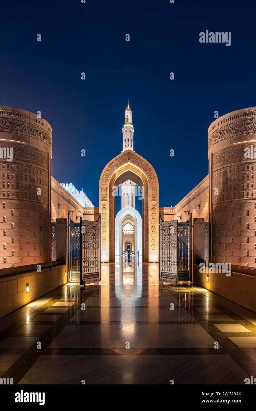 Grande Moschea del Sultano Qaboos, arco illuminato con minareto, Mascate, Oman Foto Stock