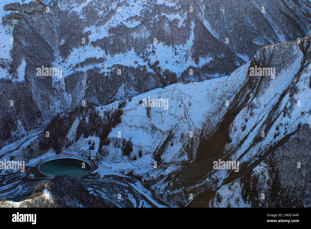 Lago freddo con acqua verde e blu a valle. Le montagne innevate circondano la gola. Paesaggio invernale in Georgia Foto Stock