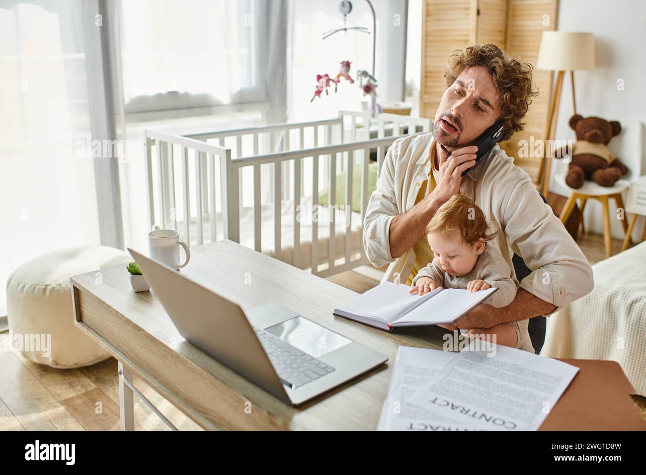 uomo che tiene le braccia, figlio neonato mentre parla sullo smartphone e lavora da casa, equilibrio tra lavoro e vita privata Foto Stock