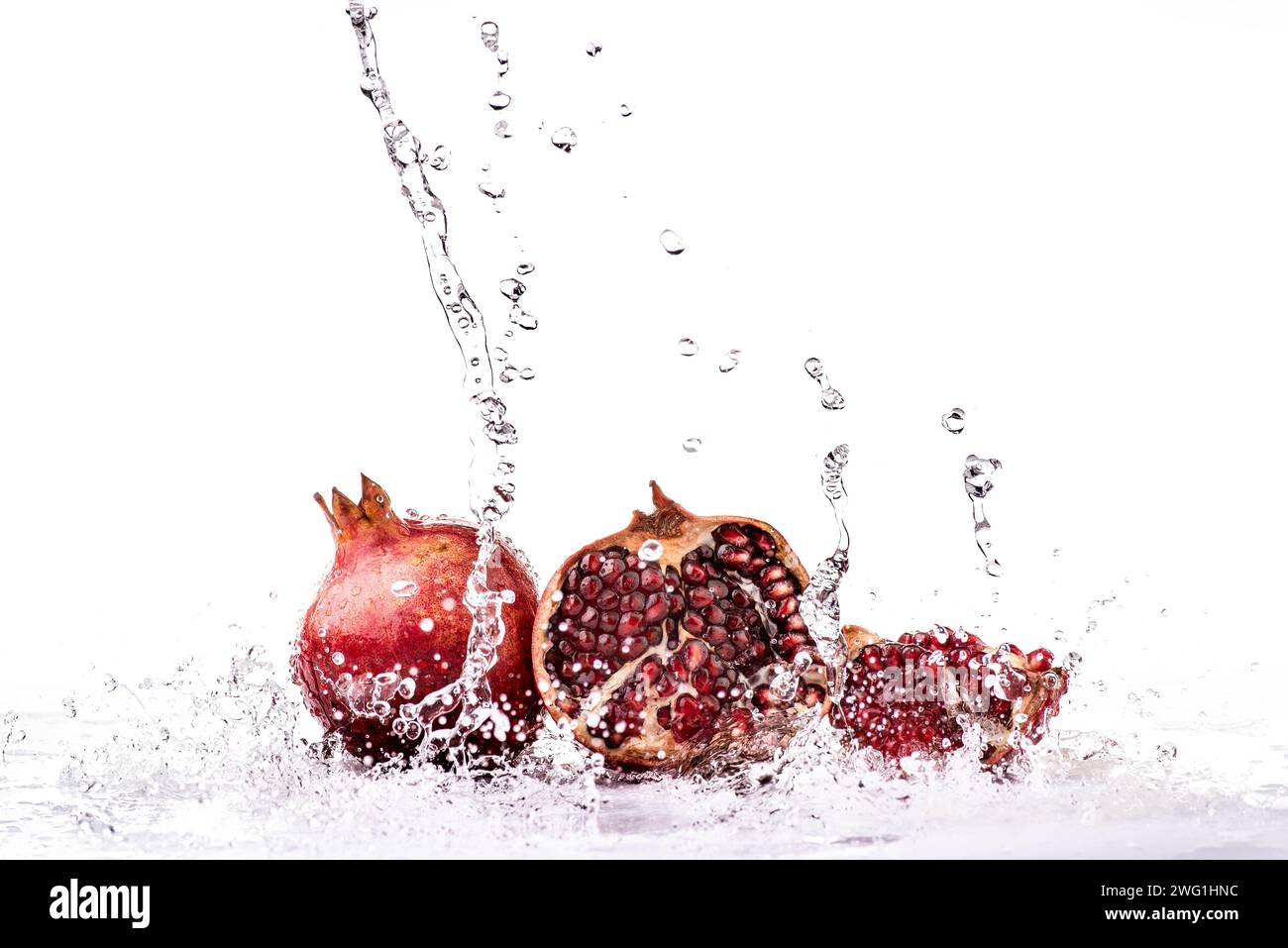 Spruzza di acqua fresca su frutti di melograno interi e grani succulenti Foto Stock