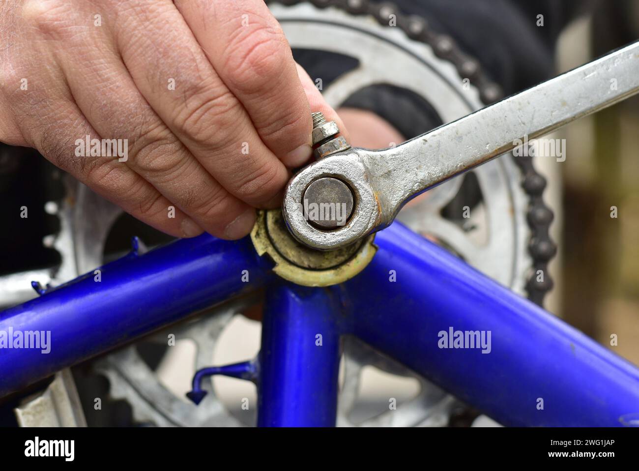 Primo piano della mano di un uomo impegnato a riparare una bicicletta. Stringe il bullone del freno della bicicletta con una chiave a bussola. Foto Stock