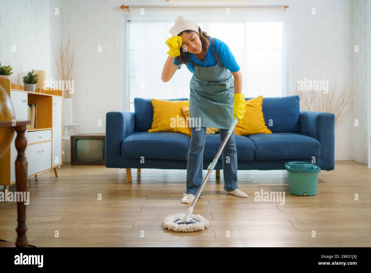 La cameriera mentre puliva il pavimento del soggiorno. Questa immagine riflette il duro lavoro e la dedizione del team delle pulizie, mostrando la c Foto Stock