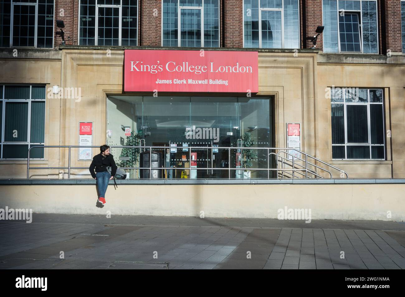 Uno studente solitario seduto fuori dall'ingresso dell'edificio James Clerk Maxwell, King's College London, Waterloo, Lambeth, Inghilterra, REGNO UNITO Foto Stock